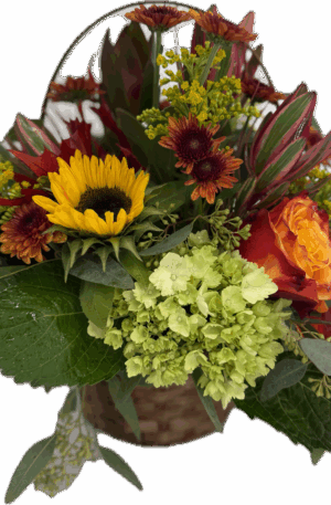 Floral arrangement in fall colors designed in a wicker basket with handle.